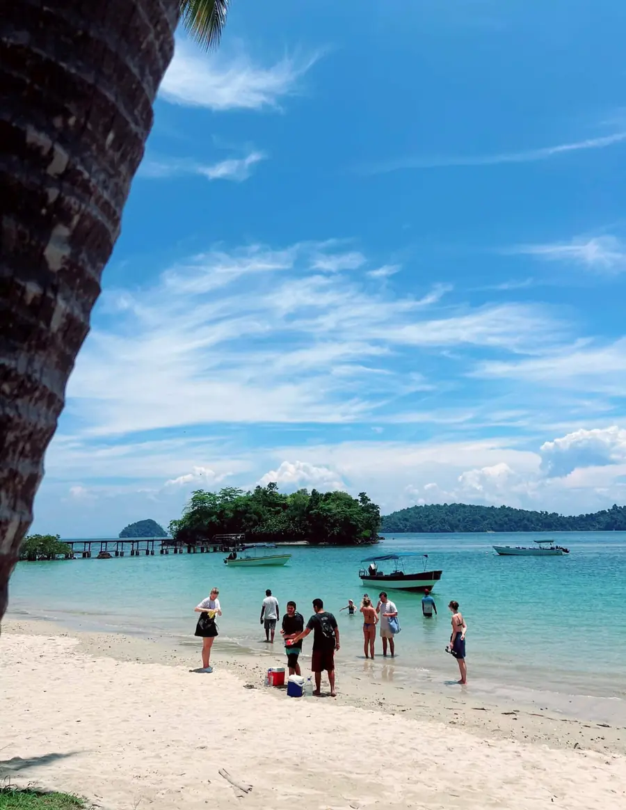 A white-sand beach with boats and a small island in Coiba National Park